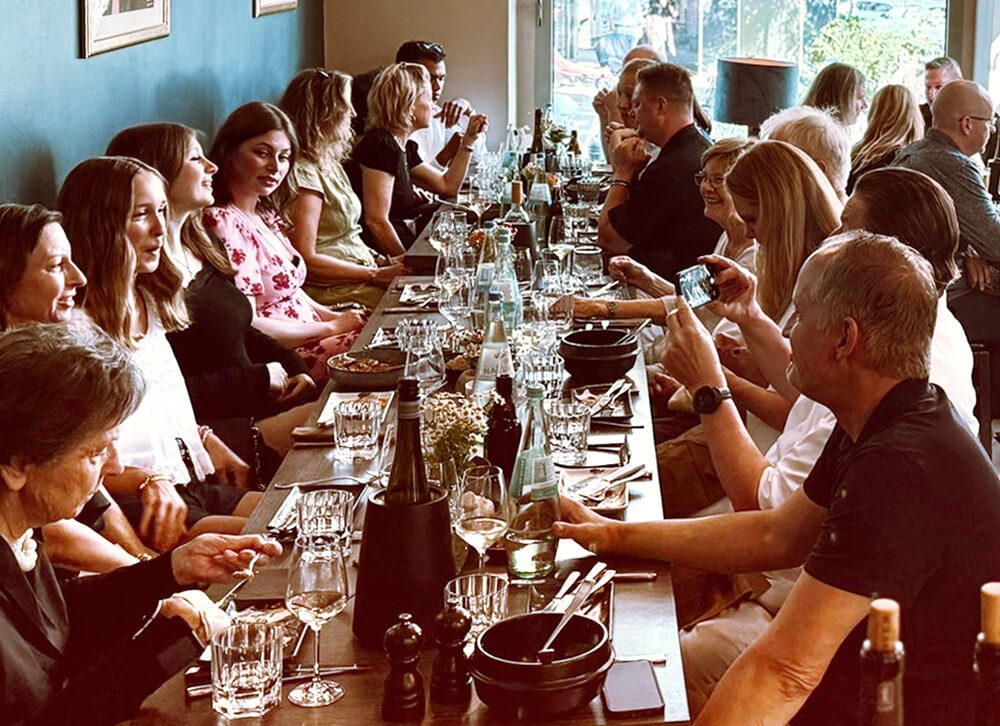 Eine besondere Location für Ihre Taufe in Düsseldorf, Gäste sitzen an einem langen Tisch und essen gemeinsam